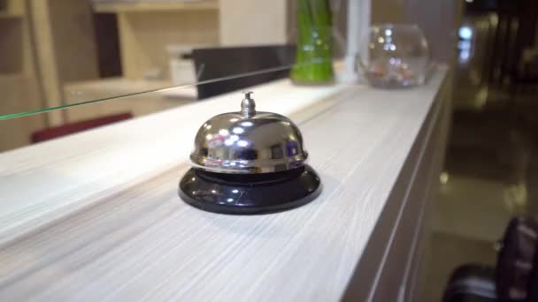 A woman's manicured hand rings the bell at the hotel reception. The metal bell reflects the Georgian flag or the red and white flag. The tourist's hand hits the bell at the hotel. - Кадры, видео