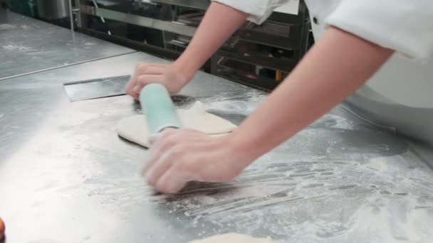 Close-up van de hand chef-kok in witte kok uniformen met schorten zijn het kneden van deeg deeg met roller, het bereiden van brood, taarten, en vers bakkerij voedsel, bakken in de oven in roestvrij stalen keuken van restaurant. - Video