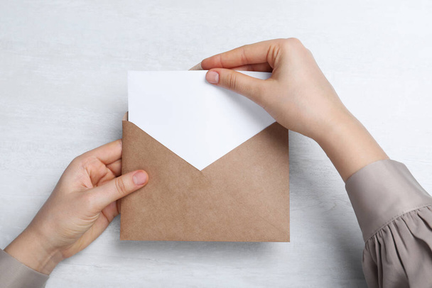 Woman taking card out of envelope at light table, top view - Photo, Image