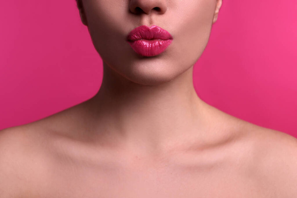 Closeup view of beautiful woman puckering lips for kiss on pink background - Фото, зображення