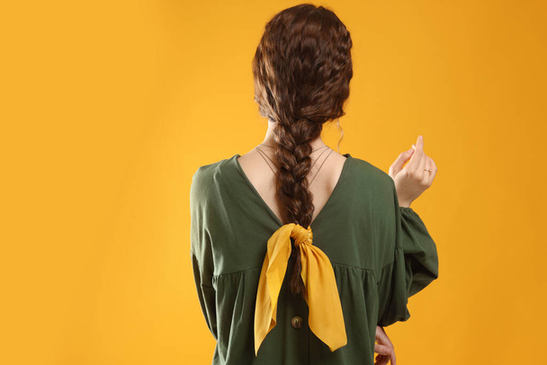 Woman with stylish bandana on yellow background, back view - Фото, изображение