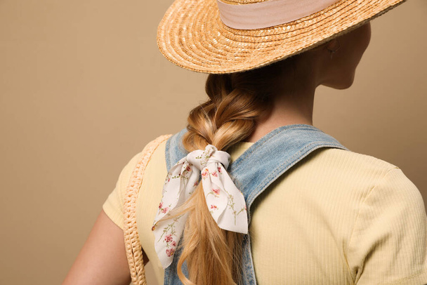 Young woman with hat and stylish bandana on beige background, closeup - Zdjęcie, obraz