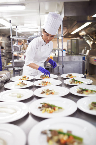 Способные руки на кухне. Снимок шеф-повара, покрывающего еду для обслуживания еды на профессиональной кухне. - Фото, изображение