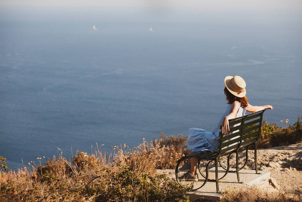 girl tourist sitting on a bench at  the observation deck and looks at the sea and a beautiful landscape, Corfu Island in Greecethe sea - Foto, imagen