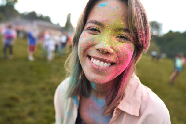 Sonriente mujer caucásica disfrutando del festival del polvo de color  - Foto, imagen