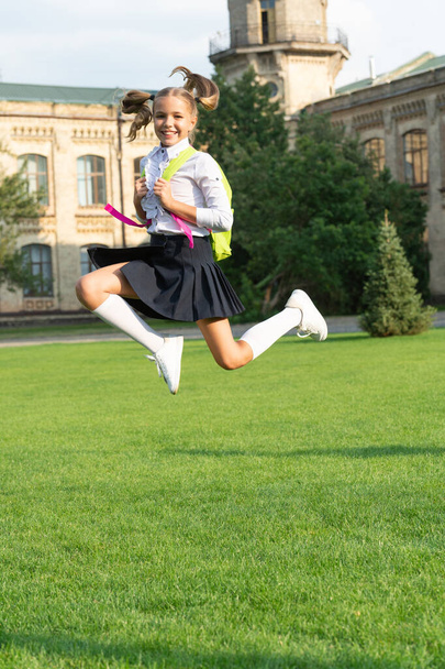 Happy energetic girl child in uniform back to school jumping for joy, September 1 - Foto, imagen