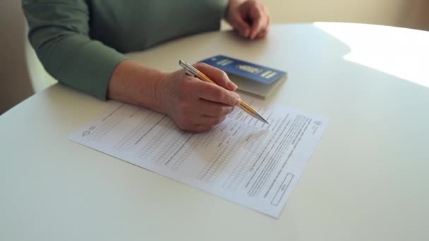 50 kaukasische Frauen der 60er Jahre schreiben mit einem Stift in PESEL Dokument auf weißem Tisch im State Service Department - Filmmaterial, Video
