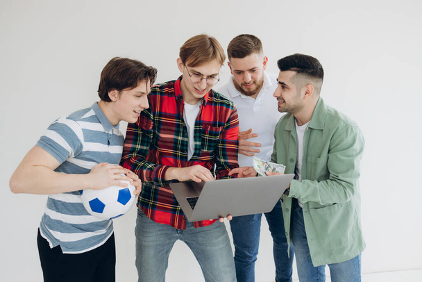 group of guys male friends looking at sports betting coupon on laptop. Decide which team to bet on. Gambling concept. Sports betting. Online betting - Fotó, kép
