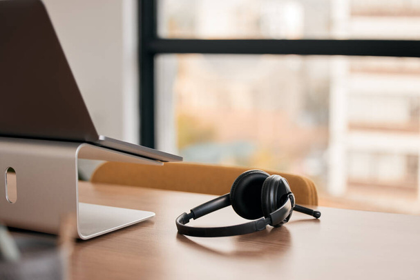 La comunicación es vital para el éxito. Bodegón de un auricular inalámbrico en un escritorio en un centro de llamadas. - Foto, imagen