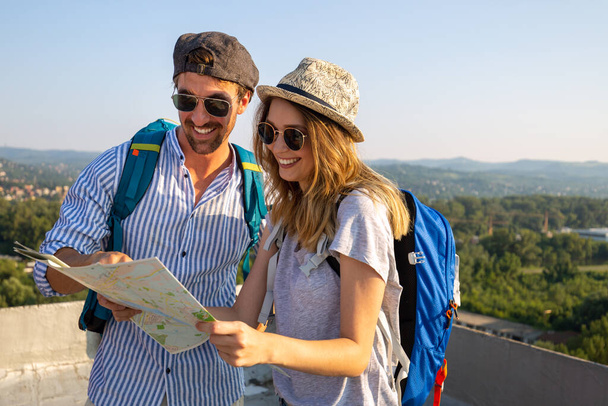 Happy young tourist couple, friends sightseeing city with map. Travel people vacation concept - Foto, Imagem