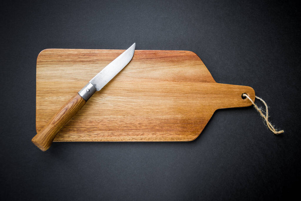 Traditional pocket knife on a wooden cutting board. Black background - Foto, Imagem