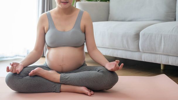 Young pregnant woman doing yoga at home, healthcare and pregnancy care concept - Фото, изображение