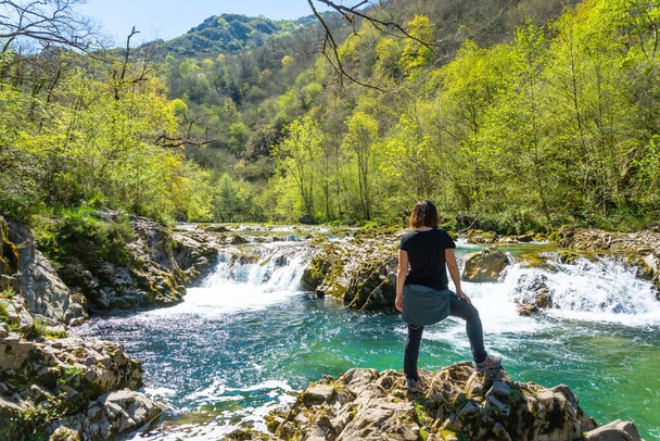 A young woman looking at the waterfalls on the Sella river between El Tornin a la Olla de San Vicente, near Cangas de Onis. Asturias. Spain - Fotografie, Obrázek