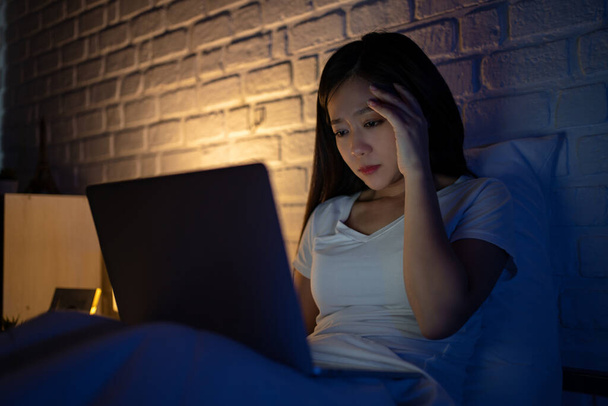 Exhausted Young business woman using laptop working late at night on bed. - Foto, immagini