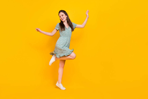 Photo of cute excited lady dressed green dress dancing empty space isolated yellow color background - Фото, зображення