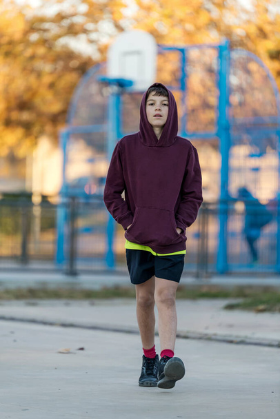 Front view of a young hooded teen male walking away - Photo, Image