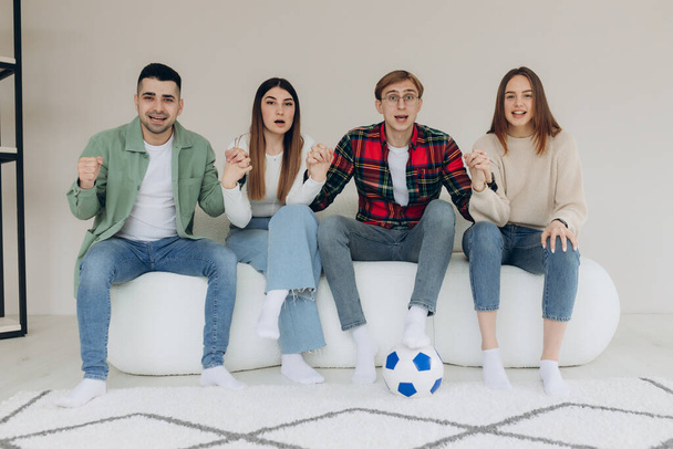Onnelliset ystävät tai jalkapallofanit katsovat jalkapalloa televisiosta ja juhlivat emotionaalisesti voittoa kotona. Ystävyyden, urheilun ja viihteen käsite - Valokuva, kuva