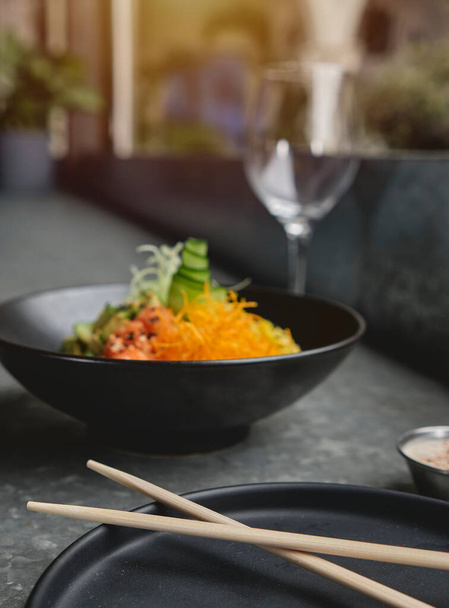 Ποκ μπολ, παραδοσιακή σαλάτα με ωμό σολομό Χαβάης, με chopsticks και χώρο για φωτοτυπίες. Επιλεκτική εστίαση. - Φωτογραφία, εικόνα