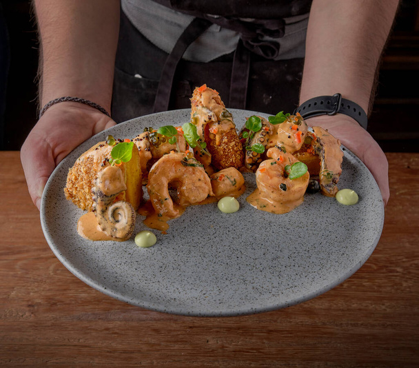 Conceptual Peruvian food, chef presenting dish, causa fried mix of seafood with golf sauce, octopus, shrimp, prawn, squid. selective focus - Photo, image