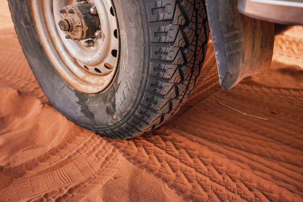 4wd vehicle tyre, dirty from dust - track print visible in red sand, closeup detail - Photo, Image