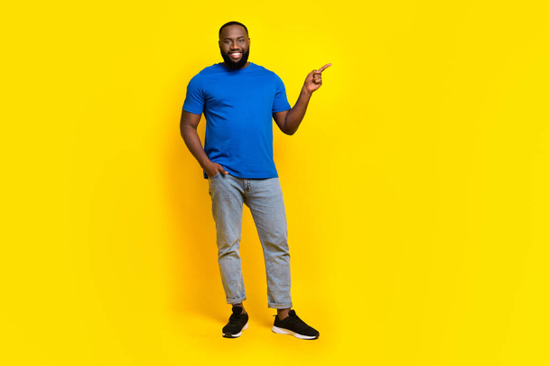 Full length body size view of attractive cheerful guy showing copy space ad isolated over bright yellow color background - Fotoğraf, Görsel