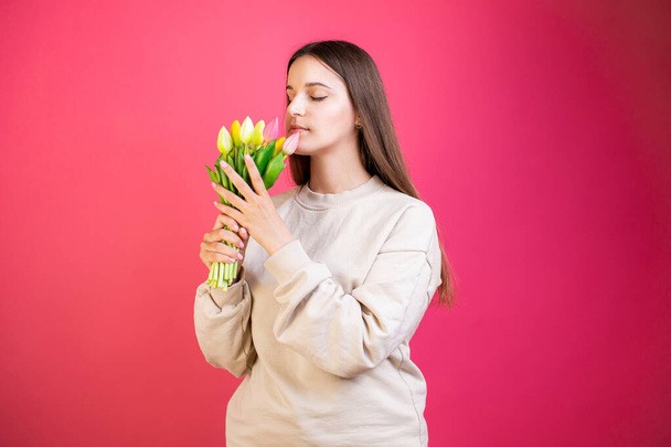 Happy young woman enjoy bouquet of tulips on pink background. - Valokuva, kuva