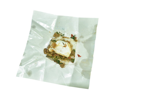 pittige roer gebakken kippendij met basilicum blad topping ei op rijst in wit papier verpakking - Foto, afbeelding