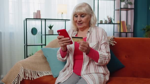 Seniorin hält Kreditkarte, gibt ihre Nummer in Handy ein, kauft online ein - Filmmaterial, Video