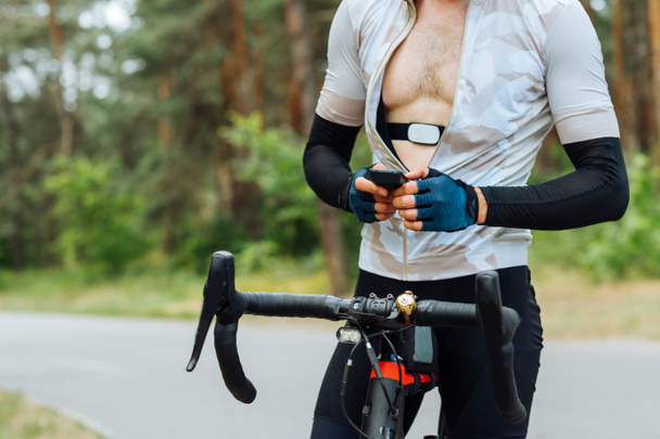 Radsportler mit Pulsmesser am Körper nutzt Fahrradcomputer beim Training im Wald vor den Toren der Stadt. - Foto, Bild