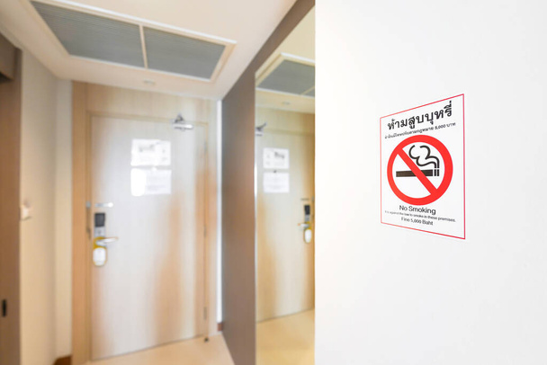 No smoking Sticker on wall beside toilet and exit door. Thai Letter on Sticker means, No Smoking. It is against the law to smoke in these premises. Fine 5,000 Baht. - 写真・画像