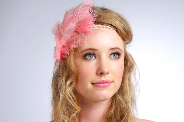 Delicate beauty. Studio shot of a beautiful young woman wearing a feathered headband. - Photo, Image