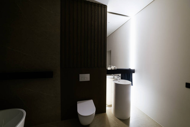 Badezimmer eines neuen Hauses mit einem großen Spiegel mit Beleuchtung und weißen Wänden - Foto, Bild