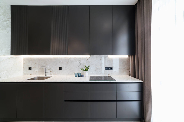 Modern interior design of a black kitchen with a white countertop - Foto, Bild