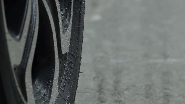 Rain splashing and car tire in rainwater. Car parking in the rain. Raining season and tires on the wet pavement. Close up of car tyre or wheels on a wet road. Represent auto in rainy season concept. - Footage, Video