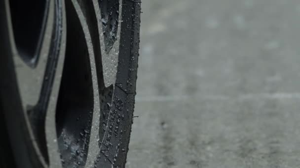 Rain splashing and car tire in rainwater. Car parking in the rain. Raining season and tires on the wet pavement. Close up of car tyre or wheels on a wet road. Represent auto in rainy season concept. - Кадры, видео