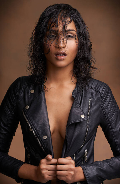 Stylish in leather. Studio shot of an attractive young woman in a leather jacket against a brown background. - Valokuva, kuva