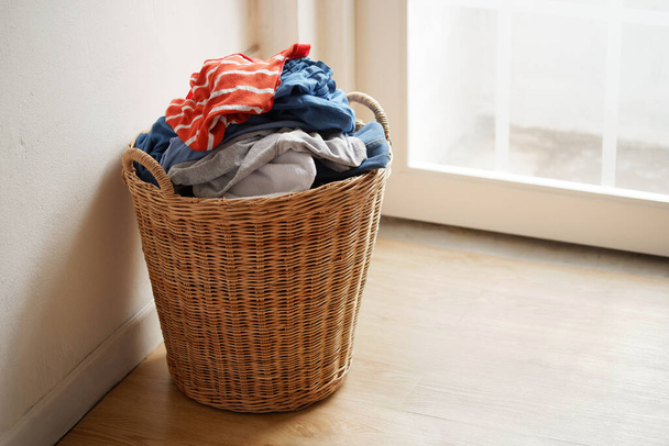 Bir sürü kullanılmış giysi taşıyan ve onları yıkamaya hazırlayan ahşap hasır sepet.. - Fotoğraf, Görsel