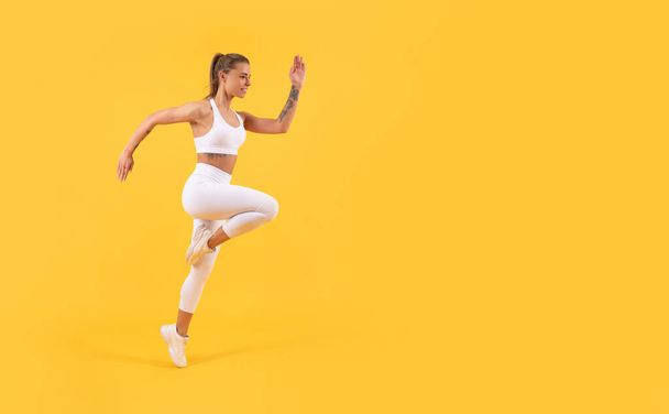 コピースペース付きで黄色い背景を走るフィットネス女子ランナー - 写真・画像