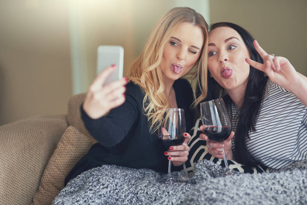 Life is better when youre crazy together. Shot of two young friends taking a funny selfie together at home. - Valokuva, kuva