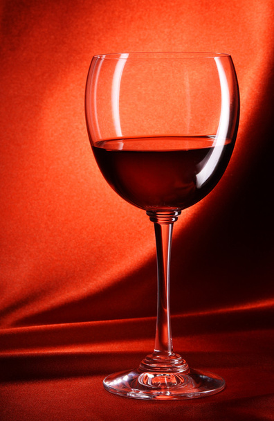 Red wine glass on a red background - Photo, Image