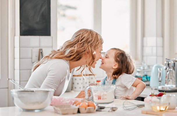 Koekjes zijn gemaakt van boter en liefde. Shot van een moeder en dochter spelen in de keuken thuis. - Foto, afbeelding