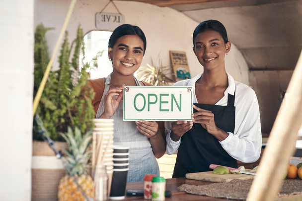 Kommen Sie und unterstützen Sie neue Unternehmen. Schüsse auf zwei junge Geschäftsfrauen mit offenem Schild in ihrem Food-Truck. - Foto, Bild