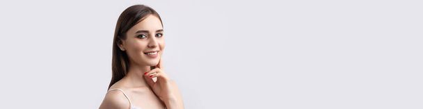 Schöne lächelnde Frau mit sauberer Haut, natürlichem Make-up und weißen Zähnen auf grauem Hintergrund - Foto, Bild
