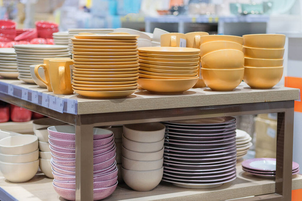 I piatti sono venduti al negozio. Righe di diverse ciotole gialle e piatti per la casa sugli scaffali di un supermercato. - Foto, immagini