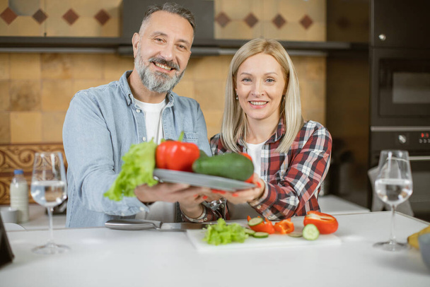 Family standing on kitchen and holding fresh vegetables - Fotografie, Obrázek