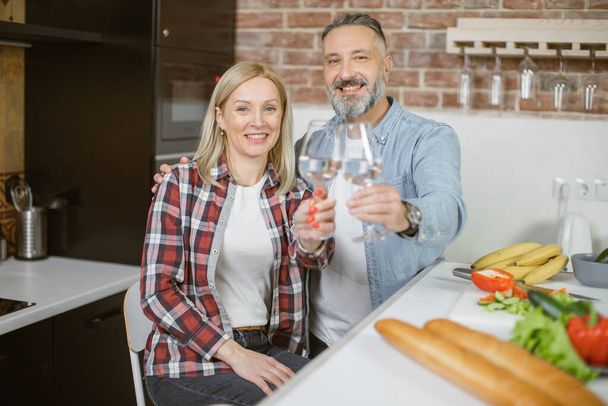 Mature couple sitting on kitchen with glasses of fresh water - Фото, зображення