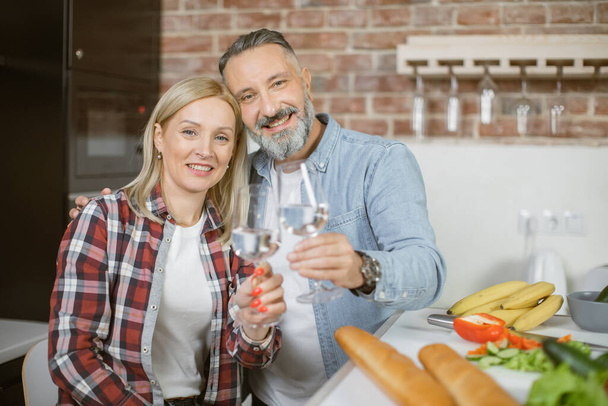 Mature couple making toast with glasses of water on kitchen - Photo, Image