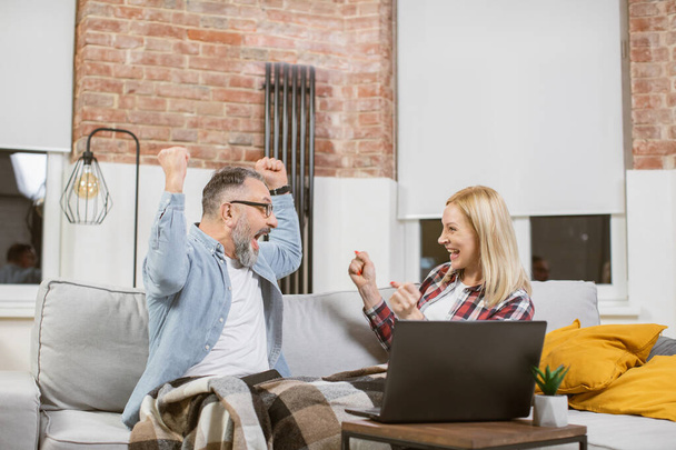 Mature couple doing yes gesture during great news on laptop - Fotó, kép