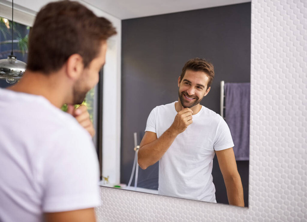 I do look good with a beard though. Cropped shot of a handsome man looking at himself in the mirror whilst touching his beard at home. - Valokuva, kuva