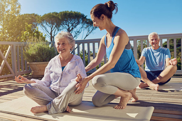 Garder la forme et rester actif. Tourné d'un couple de personnes âgées faisant du yoga avec un instructeur sur leur terrasse à l'extérieur. - Photo, image
